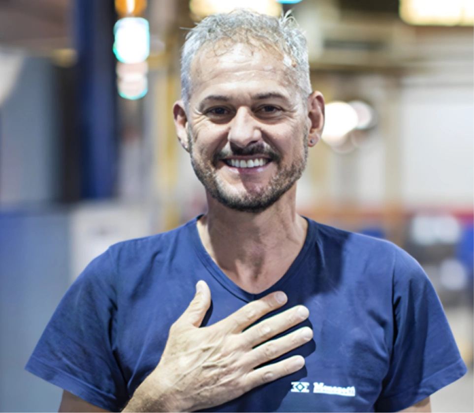 Colaborador da Menegotti sorrindo em ambiente industrial, representando um clima organizacional acolhedor, diverso e inclusivo.